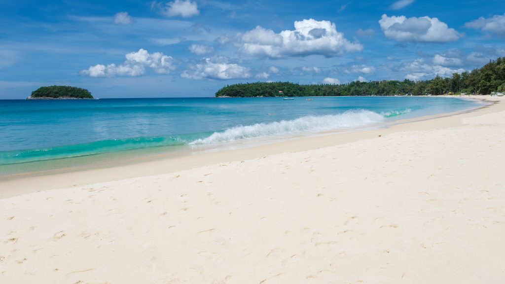 Kata beach Phuket Thailand on a sunny day with a blue sky.